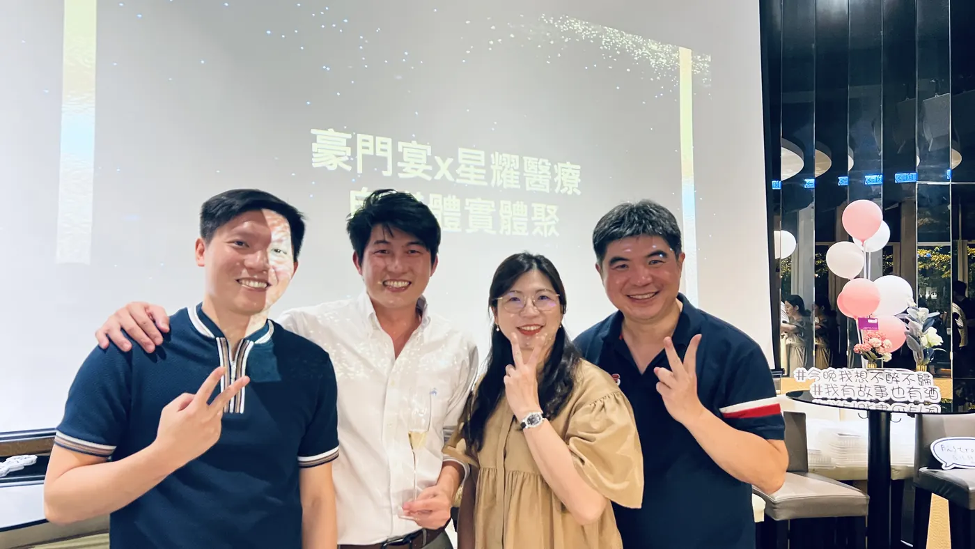 四位與會者在投影幕前比手勢合影