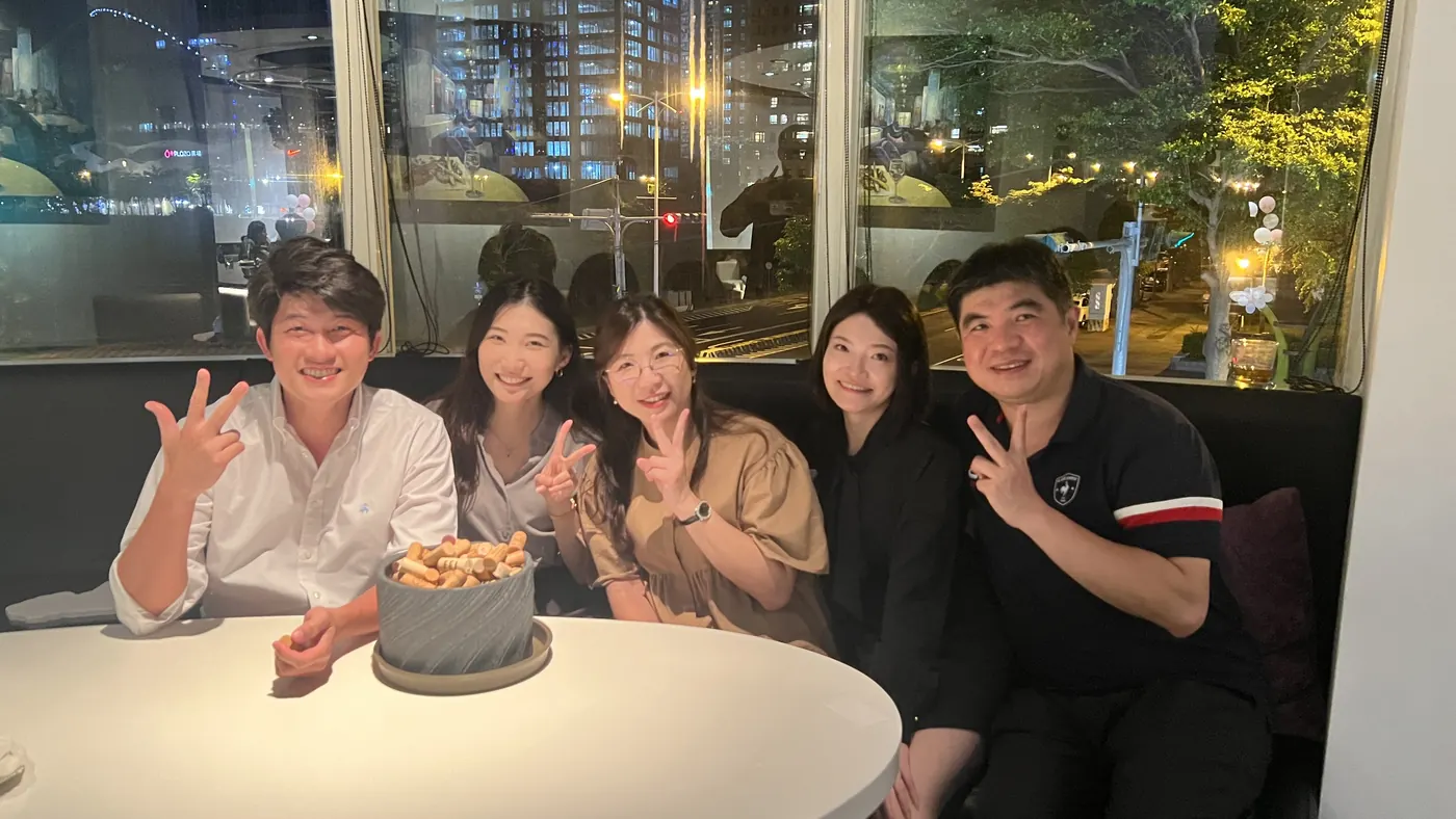 五位與會者坐在窗邊沙發座，桌上放著一盆軟木塞
