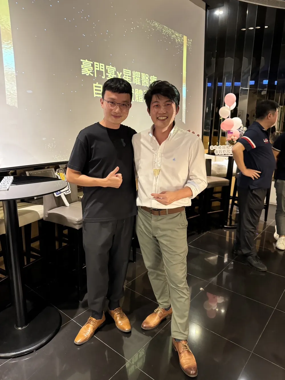 張益豪醫師與一位穿黑色上衣的與會者在投影幕前合影