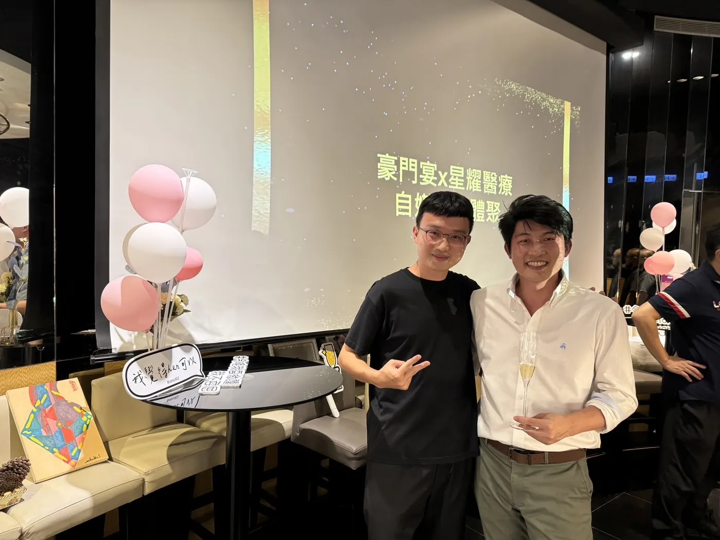 張益豪醫師與一位與會者在投影幕和氣球前合影