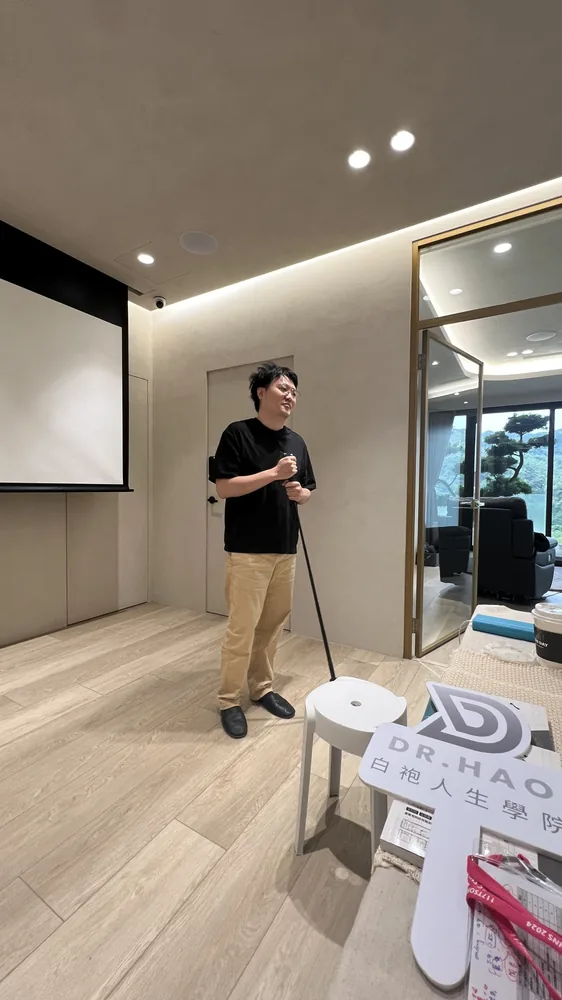 陳昱傑醫師在中午休息時手持高爾夫球桿，旁邊放著白袍人生學院立牌