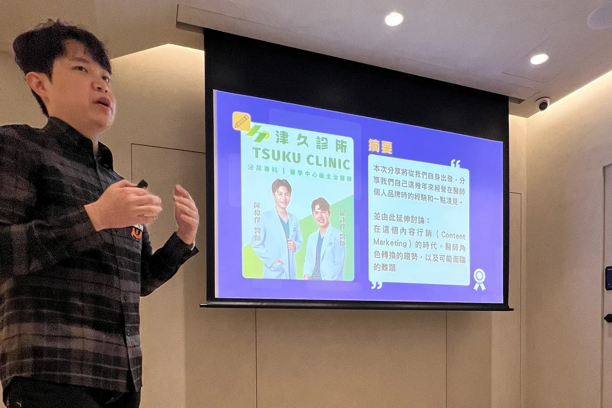 陳偉傑醫師站在印有津久診所標誌的投影片旁分享醫療自媒體經營