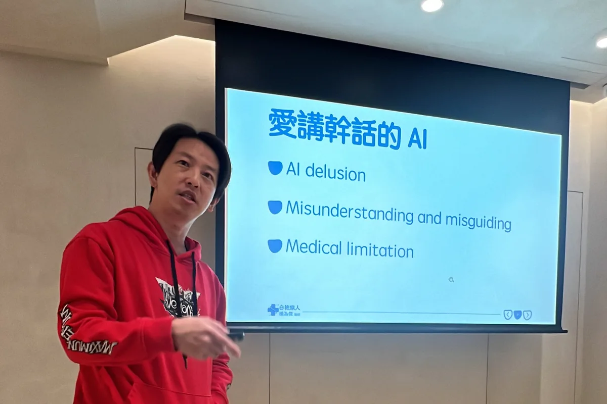 楊為傑醫師穿紅色連帽衫站在「愛講幹話的 AI」投影片旁分享