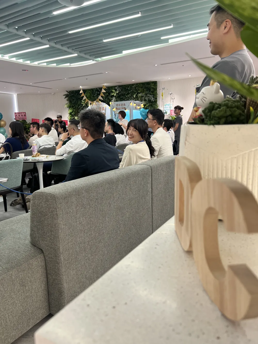 從沙發區低角度拍過去，前景是木頭做的 DC 字樣擺飾，後方與會醫師坐滿座位