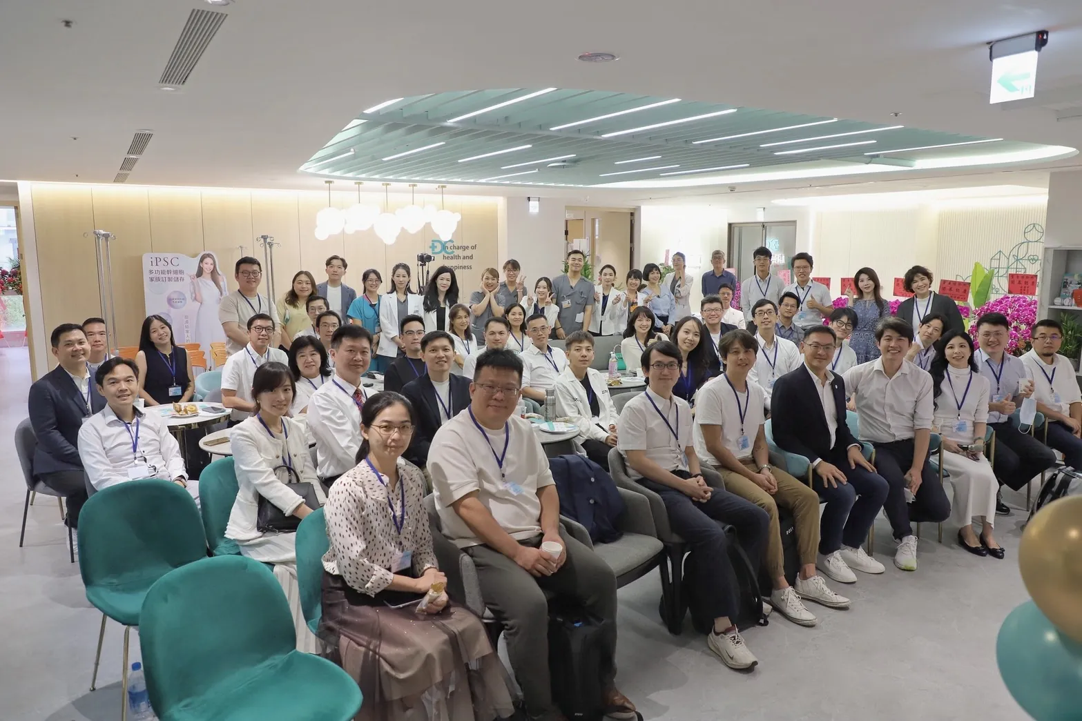 白袍人生學院竹北康博企業參訪大合照：四十多位醫師坐滿康博診所竹北分院的大廳座位區，前排坐著、後排站著，看向鏡頭
