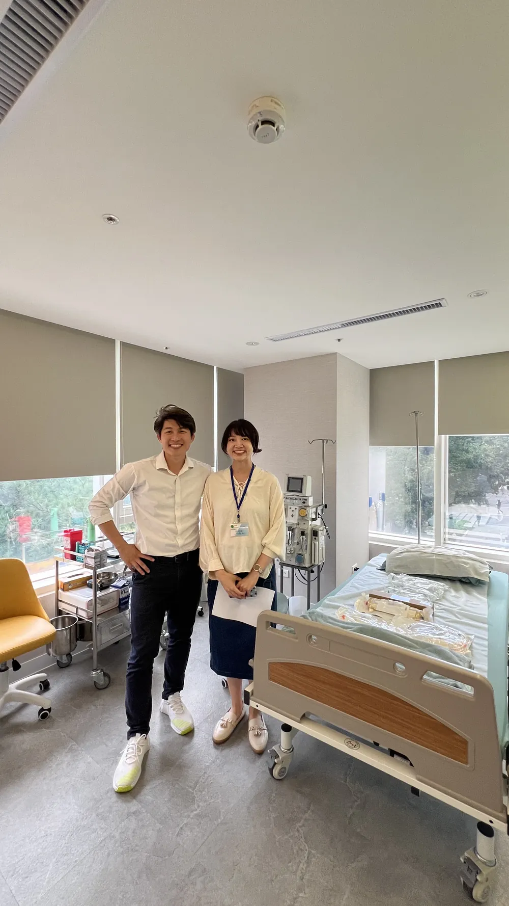 張益豪醫師與一位掛著名牌的女性在一間有病床、窗邊灑進自然光的房間裡合影